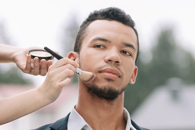 Maquilladora hace maquillaje a joven político antes de un discurso público