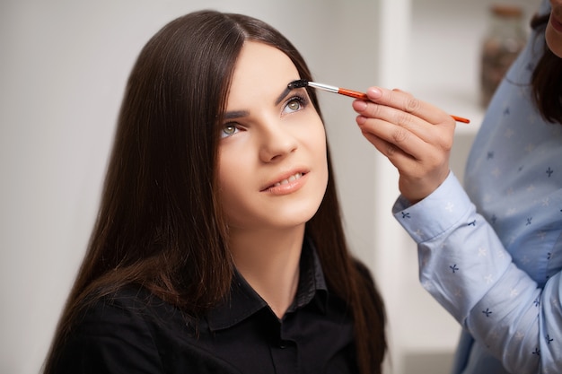 Maquilladora hace maquillaje profesional al cliente en su casa