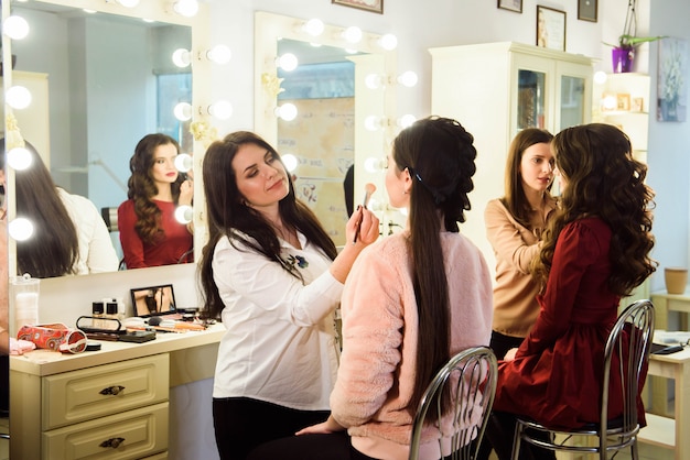 Maquilladora haciendo maquillaje profesional de mujer joven. Escuela de maquilladores