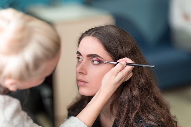 Foto maquilladora maquillando a una joven clienta