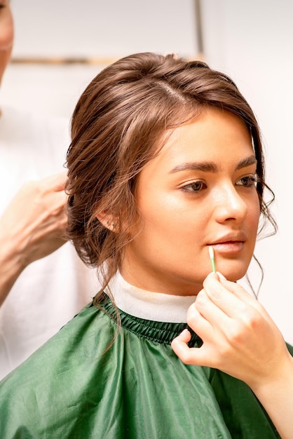 Maquilladora y peluquera preparan a la novia haciendo peinado y maquillaje en un salón de belleza