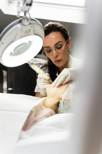 Maquilladora permanente profesional y su cliente durante el procedimiento de ruborización de labios