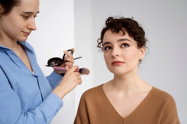 Foto maquilladora preparando modelo para sesión de fotos