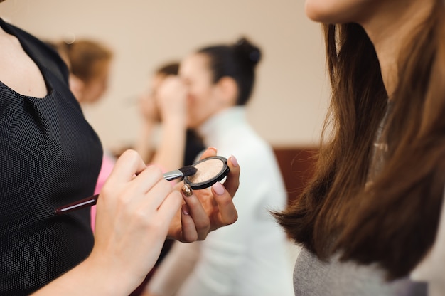 Maquilladora profesional trabajando con hermosa mujer joven.