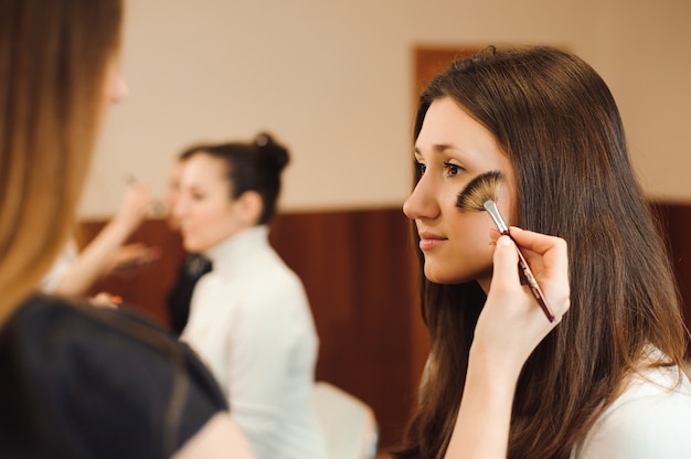 Maquilladora profesional trabajando con hermosa mujer joven.