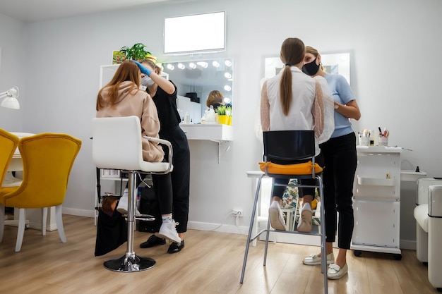 Maquilladores componen a mujeres jóvenes en salón de belleza