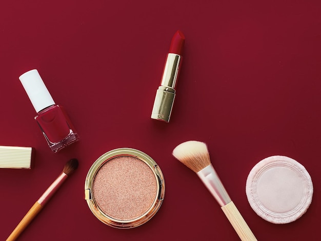 Maquillaje de belleza y diseño plano de cosméticos con productos cosméticos copyspace y herramientas de maquillaje sobre fondo burdeos concepto de estilo femenino y femenino