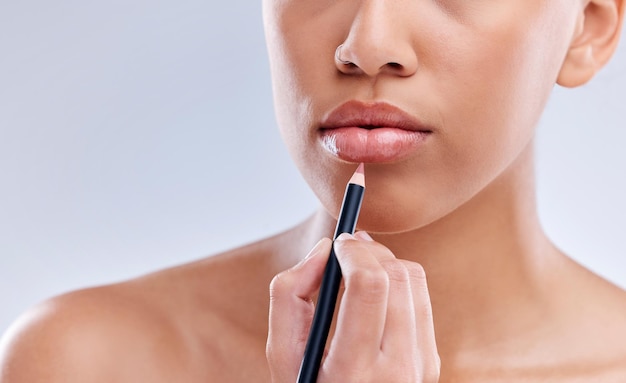 Maquillaje boca y mujer con lápiz labial en estudio para cosméticos de belleza y color sobre fondo gris Relleno y mano de modelo femenino con producto de belleza para rutina o aplicación de glamour