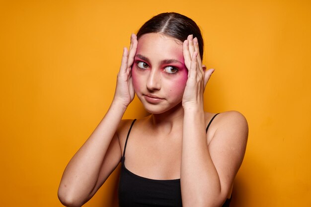 Maquillaje de cara rosa de mujer bonita posando aspecto atractivo fondo amarillo inalterado