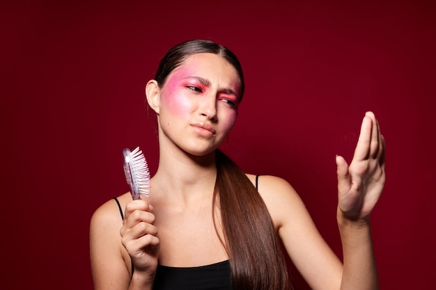 Maquillaje de cara rosada femenina de moda de belleza que presenta un aspecto atractivo con un fondo rosa peine inalterado