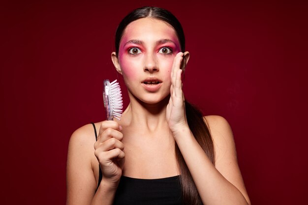 Maquillaje de cara rosada femenina de moda de belleza que presenta un aspecto atractivo con un fondo rosa peine inalterado