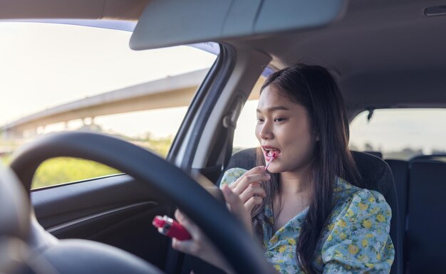 Maquillaje en el coche mujer joven aplicando maquillaje mientras conduce