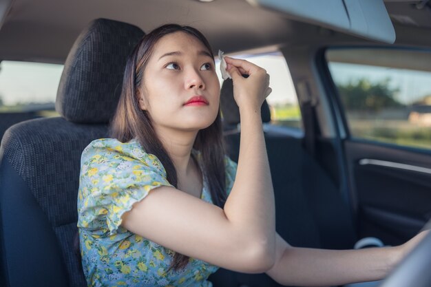 Maquillaje en el coche, mujer joven aplicando maquillaje mientras conduce