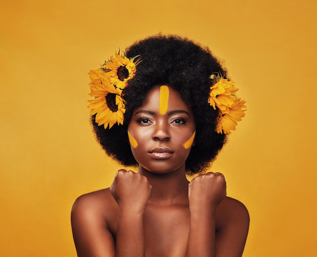 Maquillaje girasol y cabello con retrato de mujer negra en estudio para belleza creativa o primavera Cosméticos naturales y florales con cara de modelo sobre fondo amarillo para arte amor propio o brillo