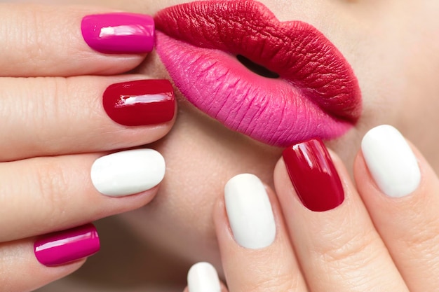 Maquillaje de labios rojo rosa y manicura de uñas.