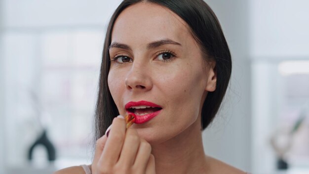 Maquillaje de labios de la señora Pov preparándose en el retrato del baño mujer sonriente aplicando lápiz labial