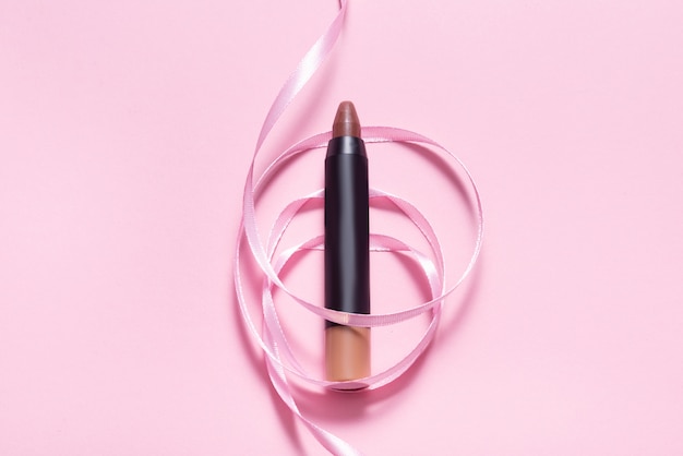 Maquillaje Lápiz labial en mesa rosa decorada con cinta rosa