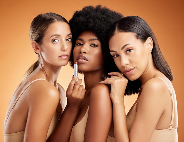 Maquillaje de lápiz labial y mujeres con productos de belleza sobre un fondo de estudio naranja Retrato facial de un grupo de modelos con cosméticos faciales para el cuidado de la piel, bienestar corporal y diversidad de personas