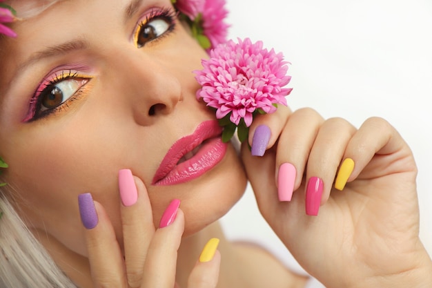 Foto maquillaje y manicura en uñas largas de mujer con áster.