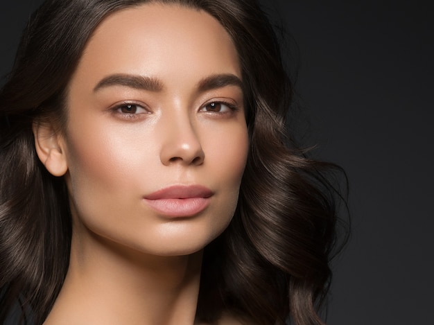 Maquillaje natural del pelo negro rizado del fondo negro femenino de la belleza asiática. Tiro del estudio.