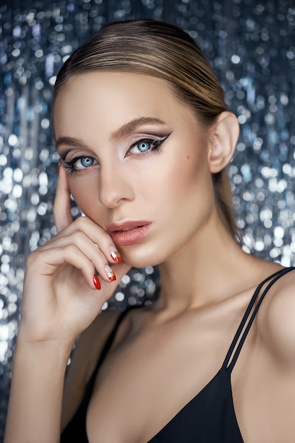 Maquillaje de ojos de noche hermosa de una mujer rubia sobre un fondo brillante. Retrato de primer plano de una mujer, maquillaje de ojos perfecto, cuidado de la piel