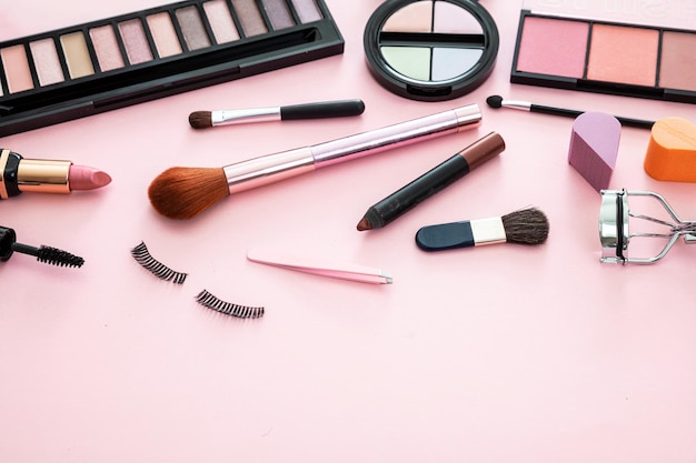 El maquillaje de los productos cosméticos contra un fondo de color rosa