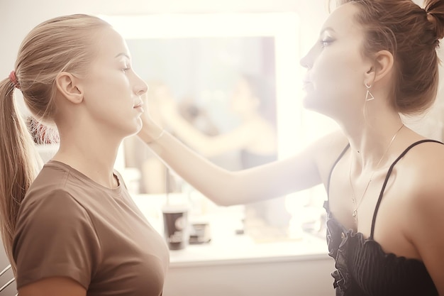 maquillaje profesional en el salón de belleza / maestro hace un maquillaje profesional de verano fresco de una hermosa modelo en el salón