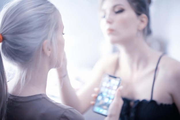 maquillaje profesional en el salón de belleza / maestro hace un maquillaje profesional de verano fresco de una hermosa modelo en el salón