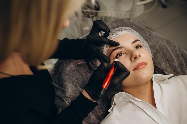 Maquillaje de tatuaje permanente en pestañas de ojos de mujer joven en salón de belleza