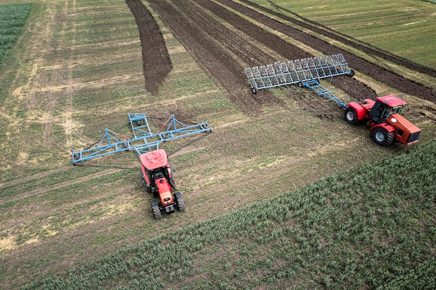 Máquina agrícola colhendo colheita em campos Trator puxa um mecanismo para feno Colheita no outono de manhã ao amanhecer agronegócio na região de Altai Rússia vista aérea de cima