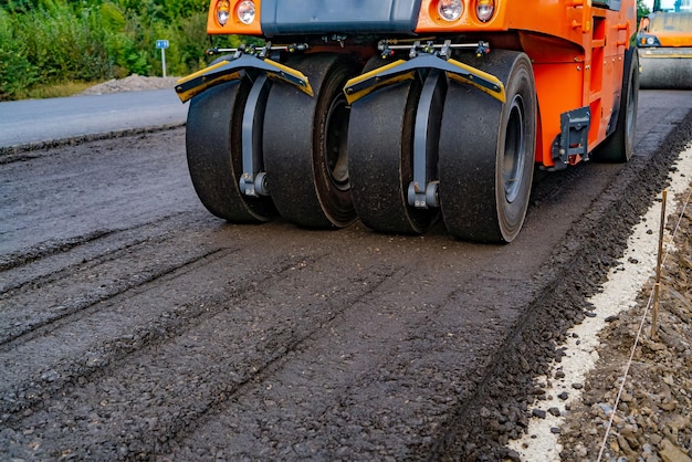 La máquina apisonadora trabaja sobre asfalto Vista de cerca de la apisonadora trabajando en el nuevo sitio de construcción de carreteras