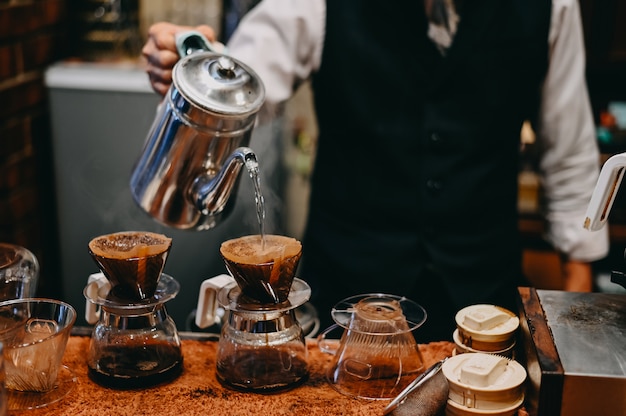 Máquina de café barista de tiro recortado Viejo hombre que gotea un café en una cafetera con tono vintage.