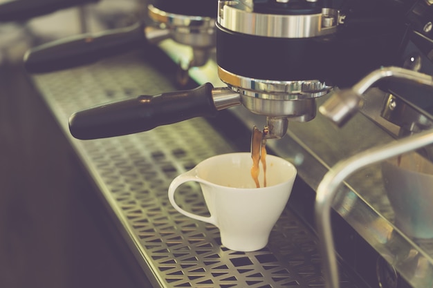 Máquina de café espresso profesional moderna que prepara café recién hecho y se vierte en una taza blanca