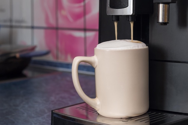 La máquina de café hace capuchino en la mesa de la cocina.