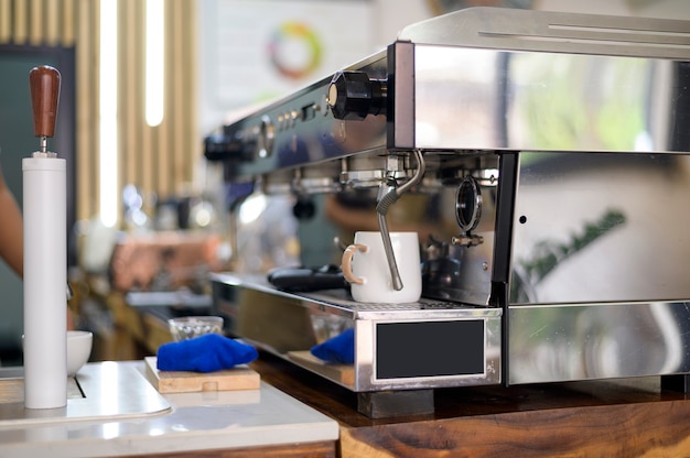 Máquina de café haciendo café negro y vertiendo en una taza en el café