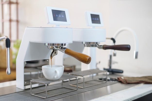 Máquina de café haciendo café negro y vertiendo en una taza en el café