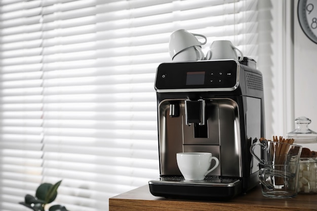 Máquina de café moderna con taza en la oficina Espacio para texto