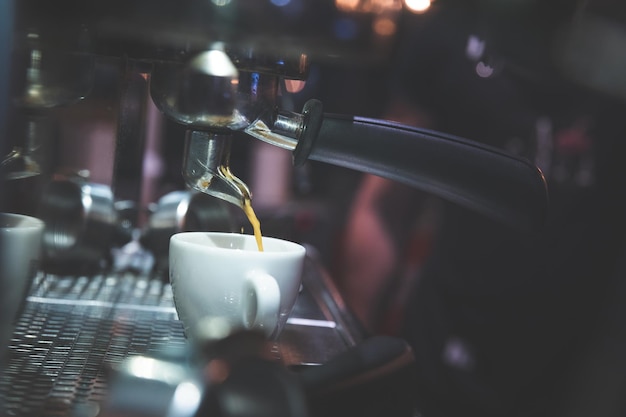 Máquina de café poniendo café en una taza blanca.