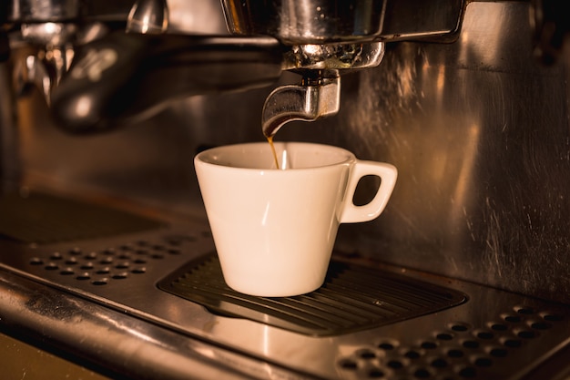 Máquina de café poniendo un descafeinado en una taza blanca