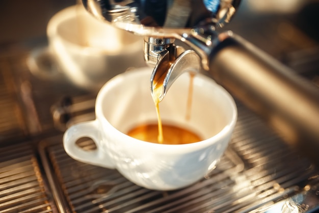 Máquina de café vierte espuma en el primer plano de la taza