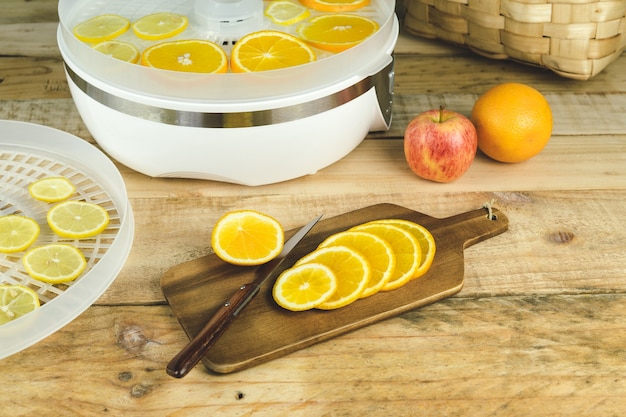 Máquina casera para deshidratar alimentos con rodajas de naranja en la mesa de la cocina.