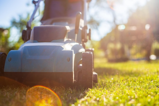 Máquina cortadora de césped sobre hierba verde en un moderno jardín o patio trasero Máquina para cortar césped Herramientas y equipos de cuidado de jardinería