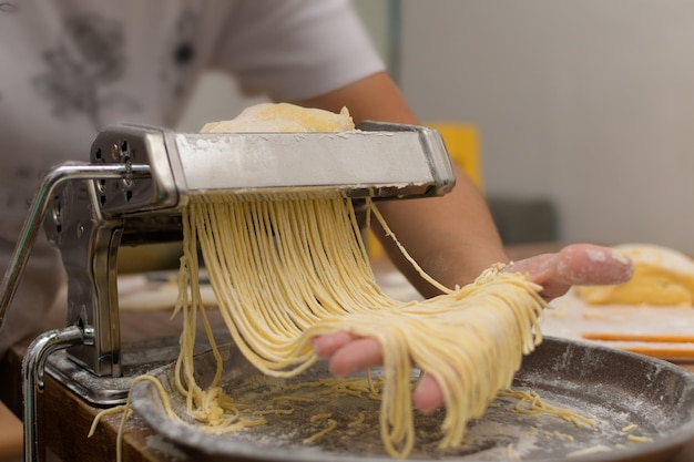 Máquina cortando la masa y haciendo fideos caseros.