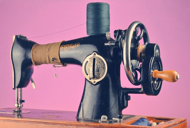 Máquina de coser antigua, vintage aislada sobre un fondo rosa pastel