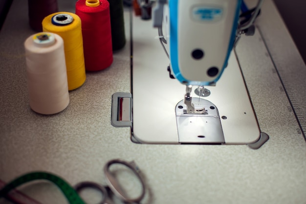 Una máquina de coser con equipamiento. Fabricación de ropa y concepto de moda.