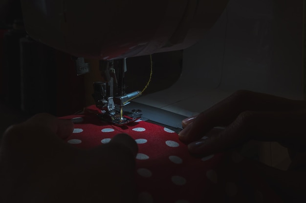 Una máquina de coser se muestra de cerca iluminada únicamente con su luz de trabajo