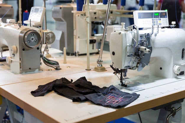 Máquina de coser y tela en taller de corte, nadie, fábrica de ropa. Producción de telas, fabricación de costura, tecnología de costura.