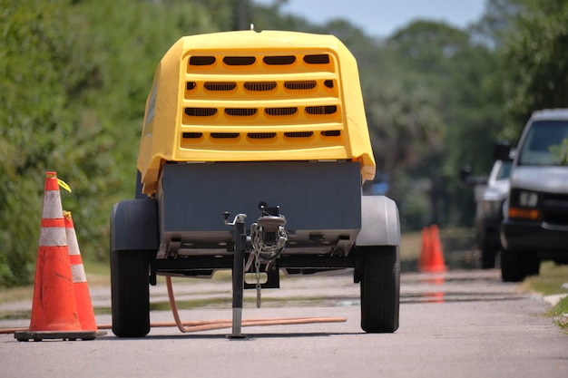 Máquina de britadeira amarela com reboque de compressor no canteiro de obras de estradas