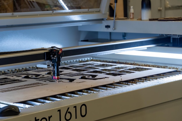 Foto máquina de corte a laser cortando folhas de madeira enquanto um homem grava o processo méxico