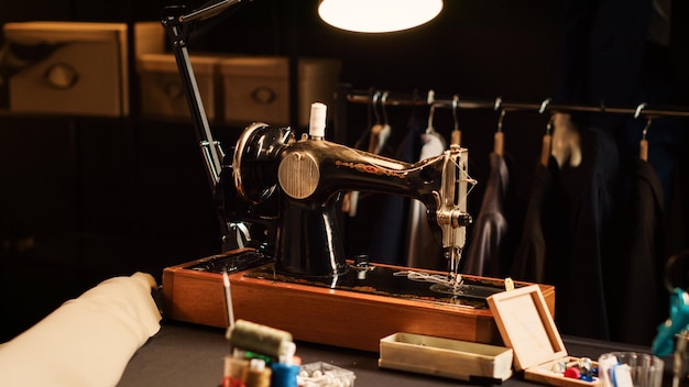 Máquina de costura da velha escola no atelier, indústria da moda com ferramentas de alfaiataria usadas para criar uma linha de roupas personalizadas. Indústria têxtil com instrumentos profissionais e estações de trabalho. Close up.